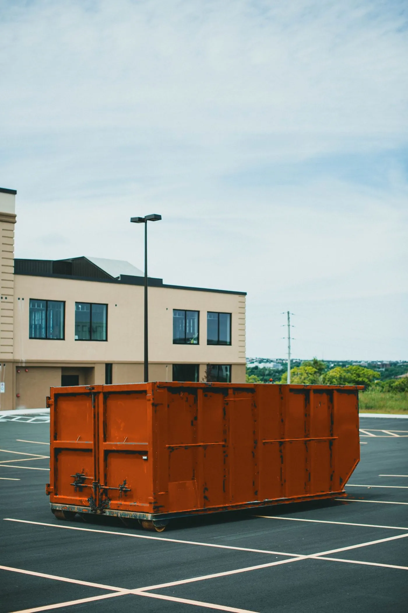 Roll-off container positioned on a paved parking lot